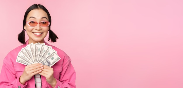 El concepto de microcréditos y préstamos rápidos entusiasmó a una elegante chica coreana mostrando dinero en efectivo y mirando