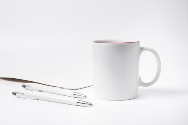 Concepto de minimalismo, taza de café y lápices en el escritorio de oficina blanco