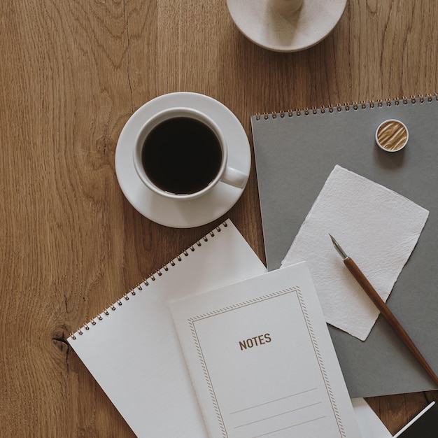 Concepto minimalista estético Hoja de papel cuaderno taza de café álbum papelería sobre fondo de mesa de madera Vista superior plana