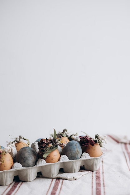 Concepto mínimo de celebración de Pascua huevos de gallina teñidos con divertidos emoticonos en paquete de cartón Huevos de Pascua de color pastel en caja de huevos sobre fondo claro con espacio de copia