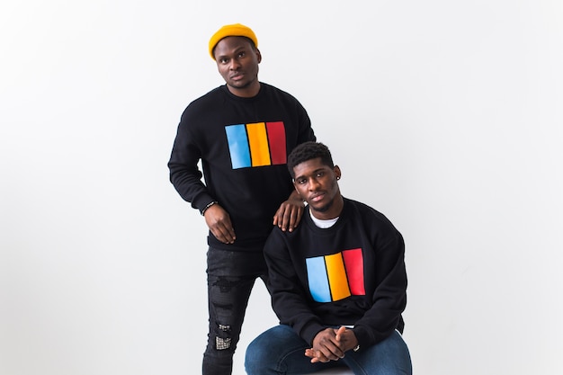 Concepto de moda y amistad de la calle - dos jóvenes afroamericanos en sudaderas negras con estilo.