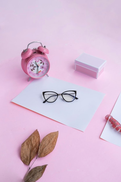 Concepto de moda y belleza acostado con gafas cuadradas accesorios de mujer sobre fondo rosa