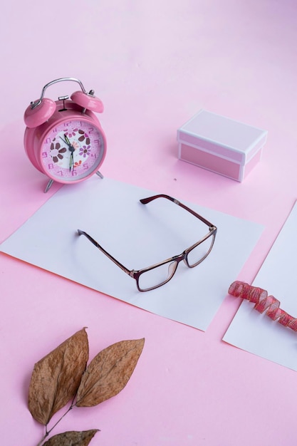 Concepto de moda y belleza acostado con gafas cuadradas accesorios de mujer sobre fondo rosa