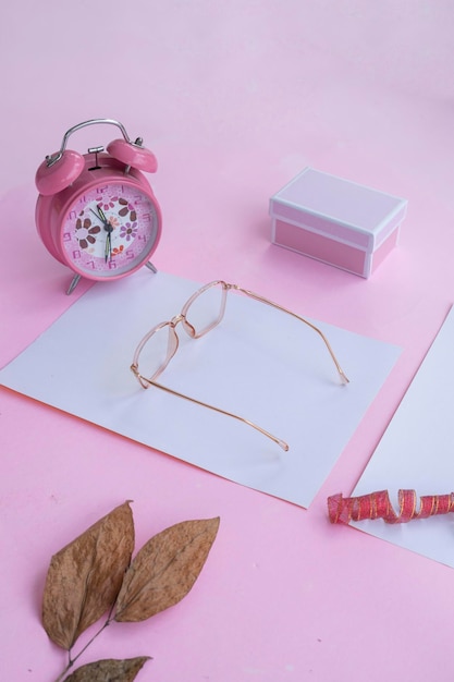 Concepto de moda y belleza acostado con gafas cuadradas accesorios de mujer sobre fondo rosa