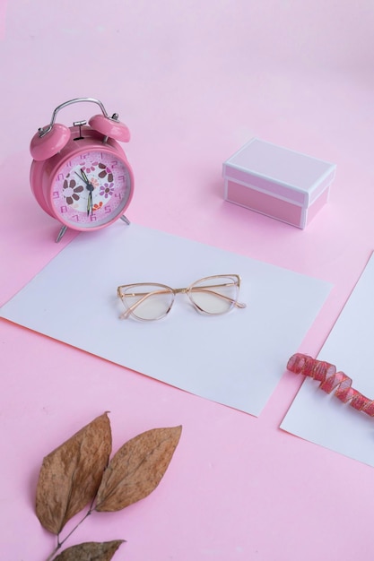 Concepto de moda y belleza acostado con gafas cuadradas accesorios de mujer sobre fondo rosa