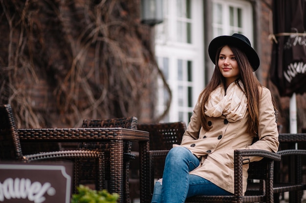 Concepto de moda callejera Retrato vintage de mujer joven con abrigo de primavera y sombrero Cabello favorecedor