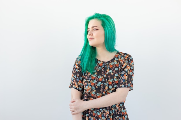 Concepto de moda, coloración del cabello y personas - Retrato de hermosa niña con cabello verde en una pared blanca