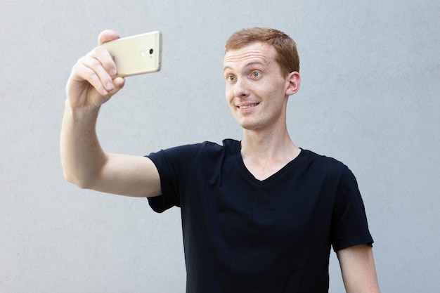 Concepto de moda, estilo, emociones y personas - Close up retrato de una pelirroja de un hermoso chico varonil con pecas. Selfie time, bloguera está haciendo una foto para su página de redes sociales.