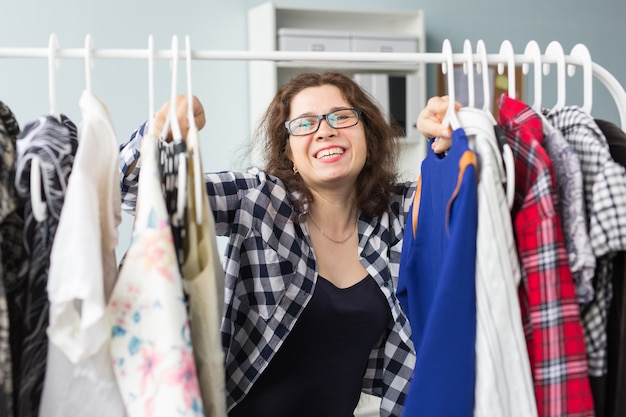 Concepto de moda, estilo y personas - mujer eligiendo ropa delante del armario completo