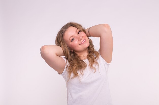 Concepto de moda, estilo y personas - mujer joven y bonita vestida con camisa blanca sobre pared blanca