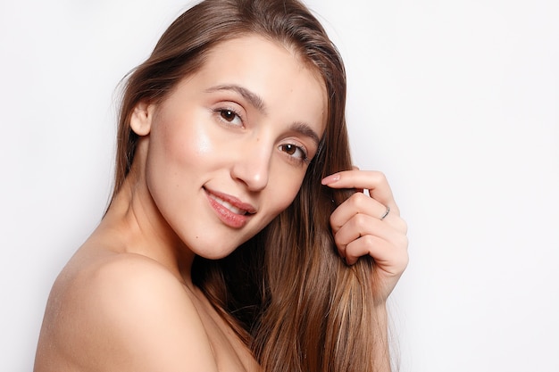 Concepto de moda, gente, juventud y belleza - Hermosa mujer sonriente con maquillaje natural, piel limpia y dientes blancos sobre fondo gris. Retrato de belleza de rostro femenino con piel natural