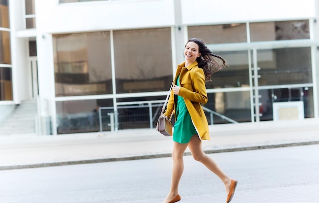 concepto de moda y gente - mujer joven feliz o adolescente corriendo en la calle de la ciudad