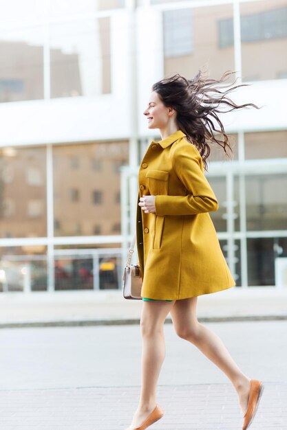 concepto de moda y gente - mujer joven feliz o adolescente corriendo en la calle de la ciudad