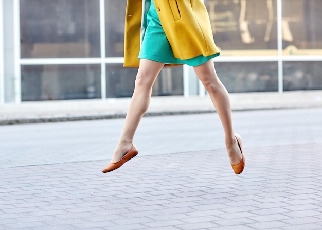 concepto de moda y gente - piernas felices de mujer joven o adolescente volando sobre el pavimento en la calle de la ciudad