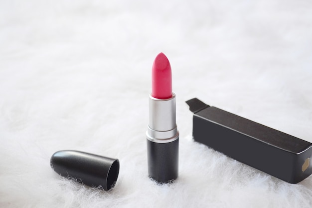 Concepto de moda. Lápiz labial rosa oscuro sobre un pelaje artificial blanco