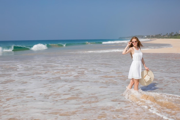 Concepto de moda de vacaciones de verano mujer bronceada con sombrero para el sol en la playa en una arena blanca tomada desde arriba