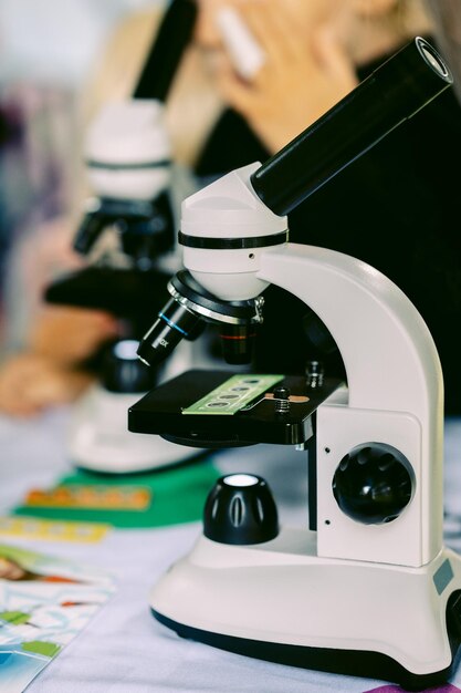 El concepto moderno de microscopio blanco en fondo borroso de la enseñanza de la bioquímica a los estudiantes y