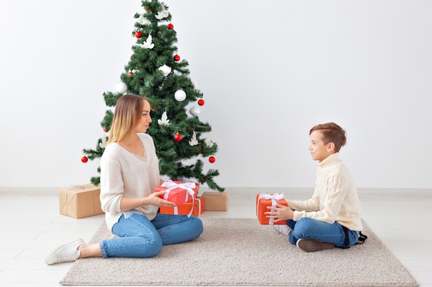 Concepto monoparental y vacaciones - Retrato de madre e hijo celebrando la Navidad en casa en la víspera de Navidad