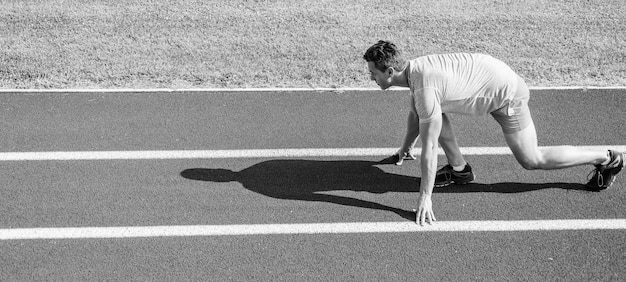 Concepto de motivación deportiva Hombre atleta corredor posición de inicio baja camino del estadio día soleado Corredor listo para ir Hacer un esfuerzo por la victoria Corredor adulto preparar la carrera en el estadio Cómo empezar a correr