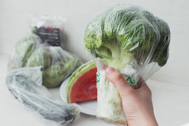 Foto concepto de movimiento de frutas y verduras sin plástico. sostenga un piede de brócoli con envases de plástico.