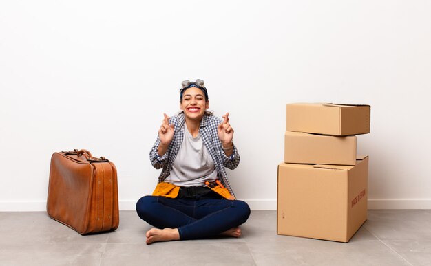 Concepto en movimiento Mujer sentada con cajas de cartón y maleta lista para moverse