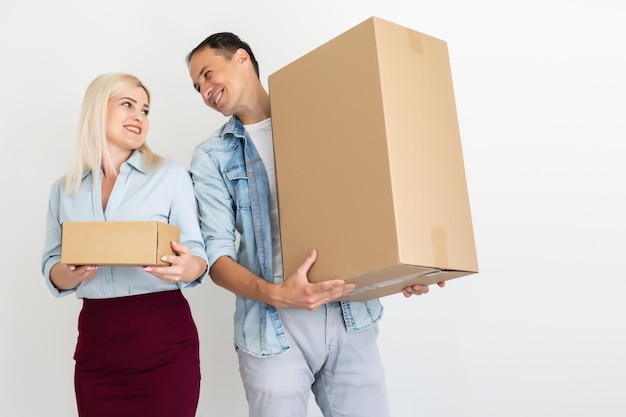 Concepto de mudanza, hogar y familia - pareja sonriente sosteniendo cajas de cartón