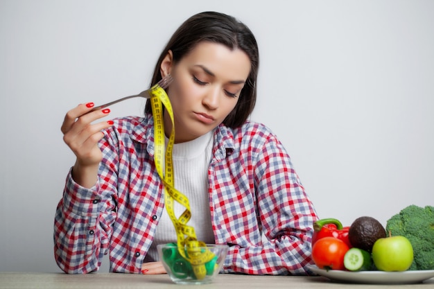 Concepto de mujer delgada con plato lleno de cinta métrica