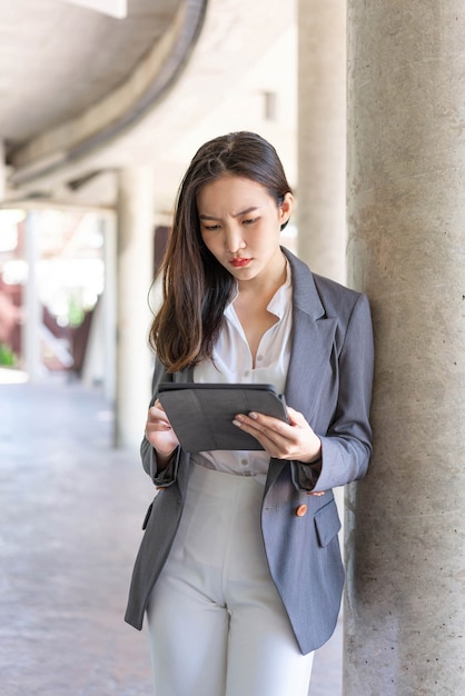 Concepto de mujer trabajadora una joven empresaria que trabaja en línea en su negocio con los dispositivos de asa, tableta, fuera del lugar de trabajo.