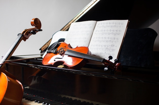 Concepto de música clásica: violonchelo, violín, piano y partitura.