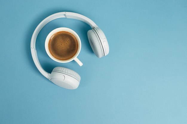 Concepto de música o podcast con auriculares y taza de café. Vista superior, endecha plana