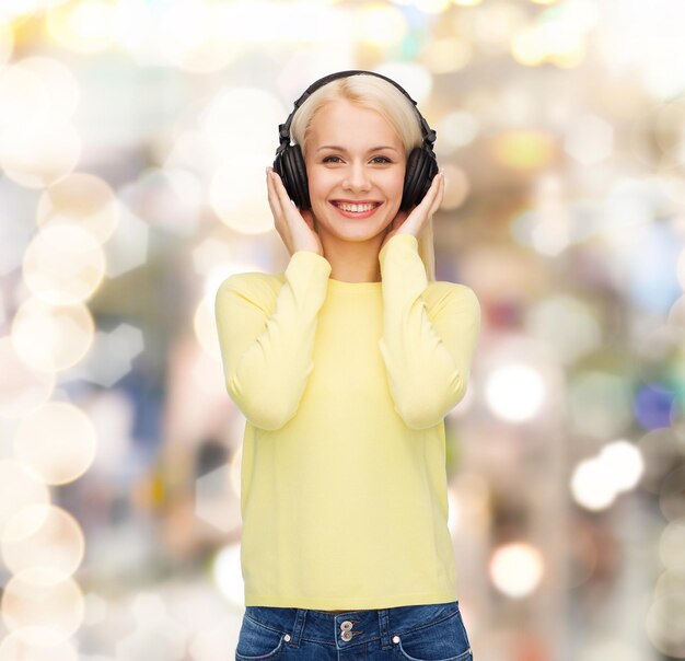 concepto de música y tecnología - mujer joven sonriente escuchando música con auriculares