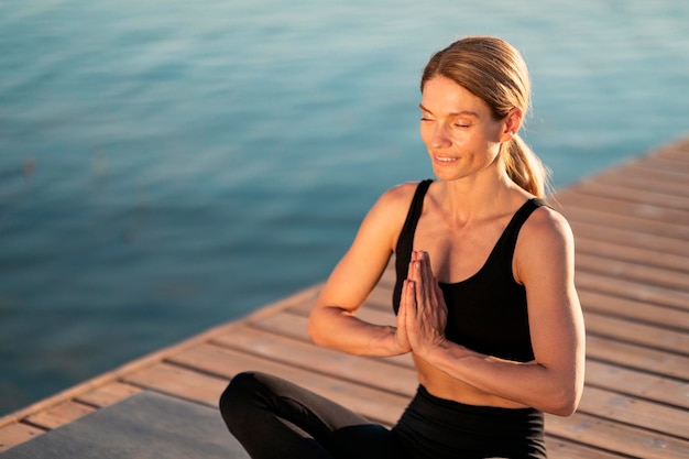 Concepto de Namaste Retrato de mujer deportiva de mediana edad relajada meditando al aire libre