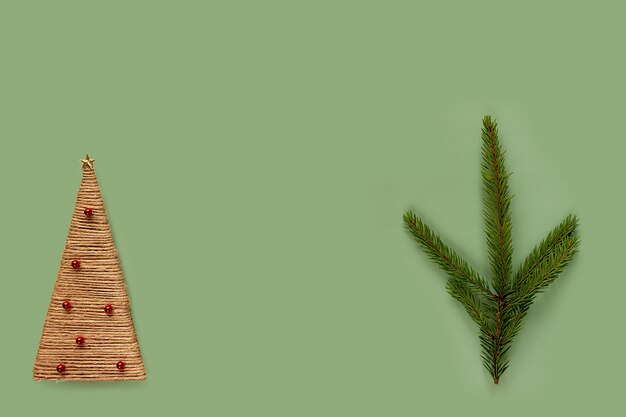 Concepto de Navidad y año nuevo. Rama de abeto y árbol de Navidad casero sobre un fondo verde, lugar para el texto