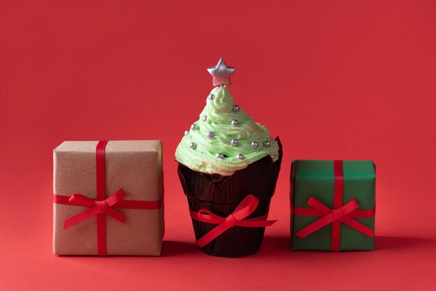 Concepto de Navidad, árbol de Navidad en forma de cupcake crema con regalos sobre fondo rojo.