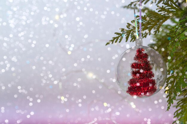 Concepto de Navidad bola transparente con un árbol de Navidad rojo en el interior, primer plano sobre un fondo de luces bokeh. Copia espacio