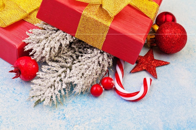 concepto de navidad. Caja de regalo roja, adornos navideños y ramas de abeto congeladas de invierno verde sobre fondo de textura de estuco congelado azul