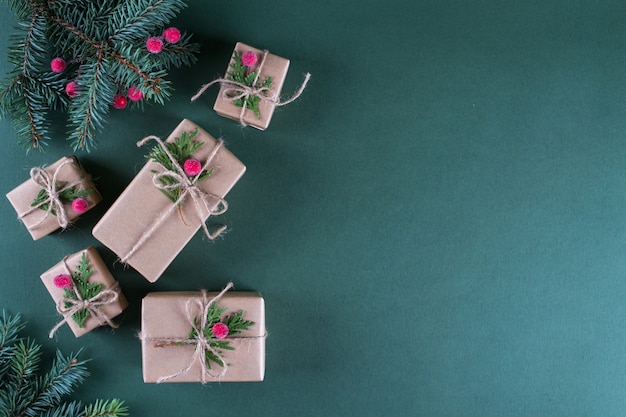 Concepto de Navidad Embalaje de regalos en papel artesanal beige vintage y decoración natural. Ramas de abeto y frutos rojos. Vista superior en plano