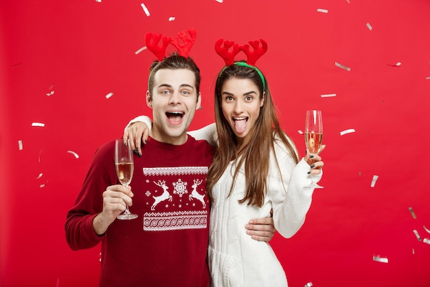 Concepto de navidad feliz hombre y mujer caucásicos con sombreros de reno celebrando la navidad brindando con flautas de champán felicitando por la navidad