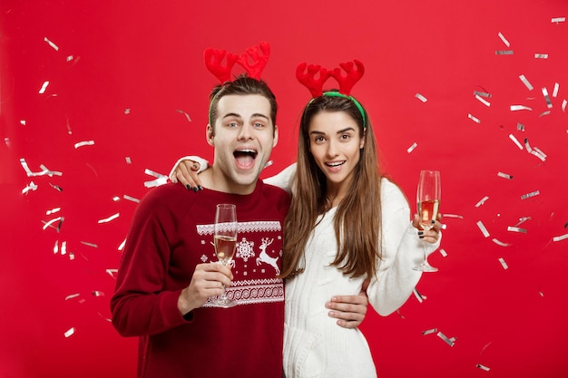 Concepto de Navidad Feliz hombre y mujer caucásicos con sombreros de reno celebrando la Navidad brindando con flautas de champán felicitando por la Navidad