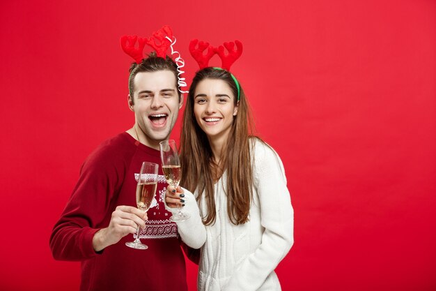 Concepto de Navidad - Feliz pareja joven en suéteres celebrando la Navidad con Champagne.