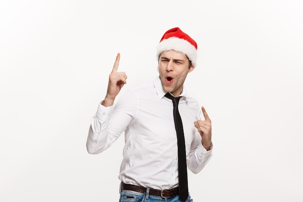 Concepto de Navidad Guapo hombre de negocios use sombrero de santa apuntando con el dedo en el lado con fondo blanco aislado