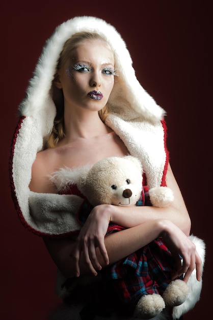 Concepto de Navidad hermosa mujer en traje de santa claus con oso de peluche ayudante de santa con