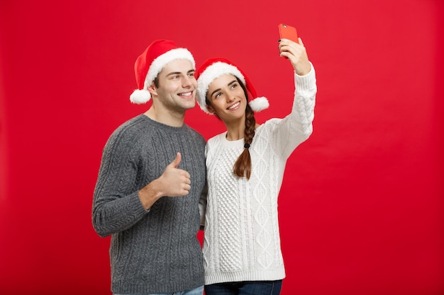 Concepto de Navidad Joven pareja atractiva tomando un selfie por teléfono móvil celebrando el día de Navidad