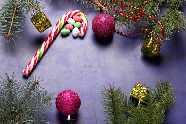 Concepto de Navidad juguetes de Navidad bastón de caramelo ramas de árboles de Navidad sobre un fondo púrpura Primer plano