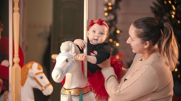 Concepto de navidad madre regordeta sonriente en suéter beige con su bebé en estudio de navidad