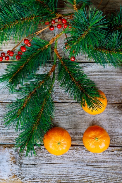 El concepto de la Navidad con las mandarinas, abeto ramifica con las especias en la tabla de madera rústica vieja. Fondo de año nuevo. Enfoque selectivo