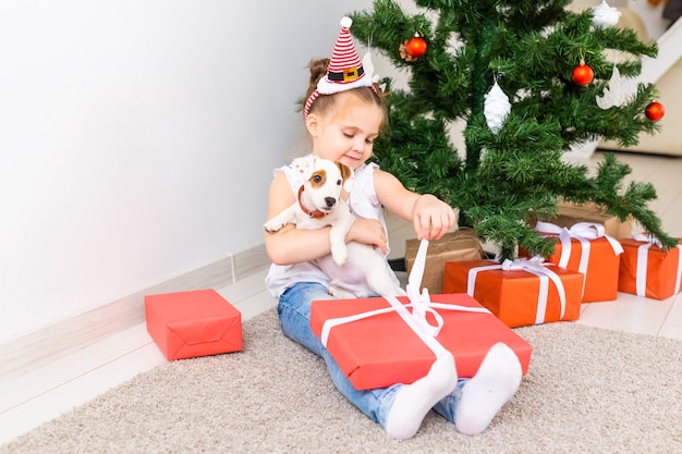 Concepto de Navidad, mascotas y vacaciones - Niño con sombrero de santa con un cachorro de jack russell terrier.