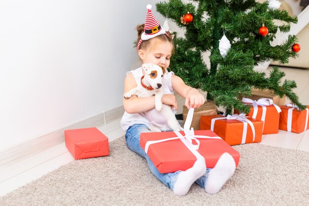 Concepto de Navidad, mascotas y vacaciones - Niño con sombrero de santa con un cachorro de jack russell terrier