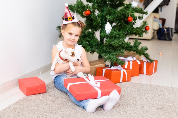 Concepto de Navidad, mascotas y vacaciones - Niño con sombrero de santa con un cachorro de jack russell terrier