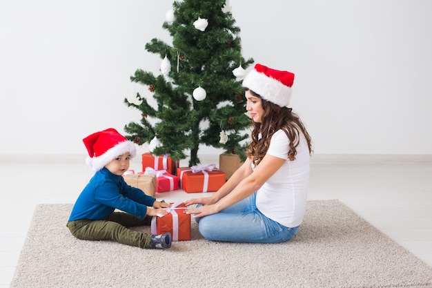 Concepto de Navidad, monoparental y vacaciones - Niño lindo con regalo de Navidad para su madre en el hogar.